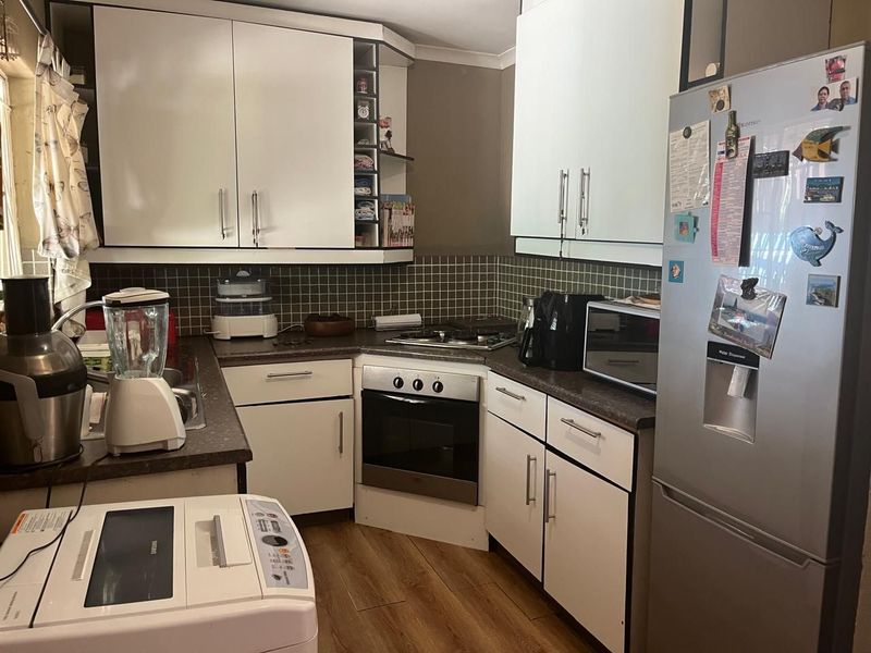 Compact kitchen featuring white cabinetry, dark laminate countertops, tiled backsplash, and integrated oven with gas hob.