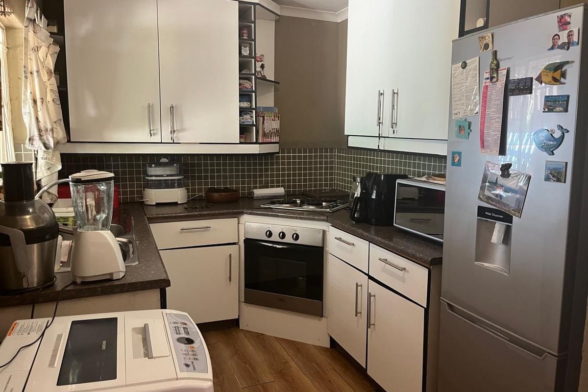 Compact kitchen featuring white cabinetry, dark laminate countertops, tiled backsplash, and integrated oven with gas hob.