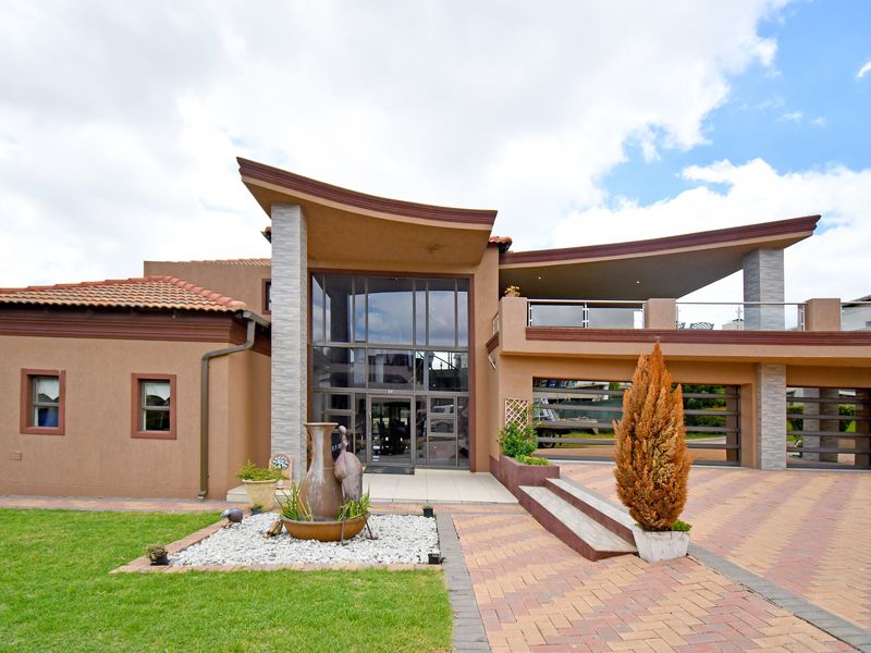 Modern architectural home featuring a striking curved roofline, expansive glass facade, double garage, and a spacious upper-level balcony.
