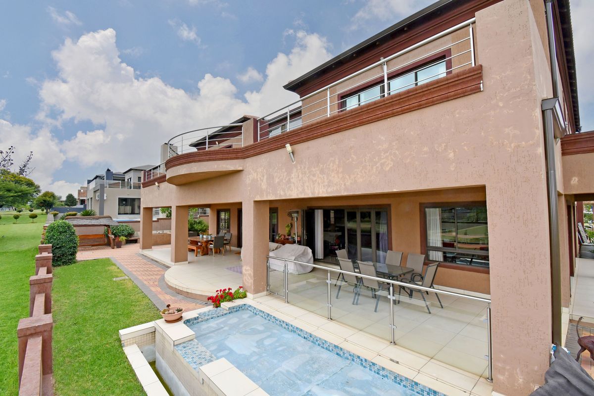 Rear view of the property featuring a covered patio, balcony with stainless steel balustrades, and a small plunge pool overlooking the garden.