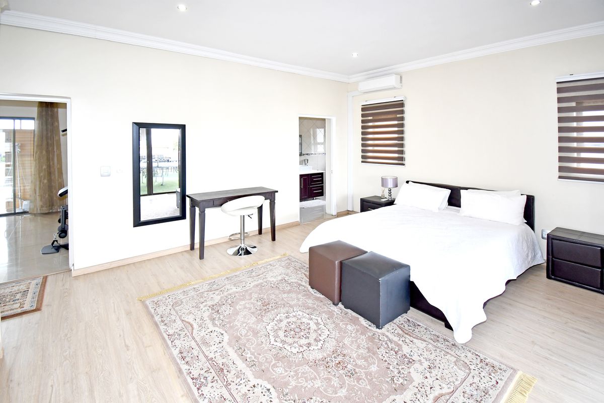 Spacious bedroom featuring light laminate flooring, recessed lighting, crown molding, and an integrated split-system air conditioner with direct access to an en-suite bathroom.