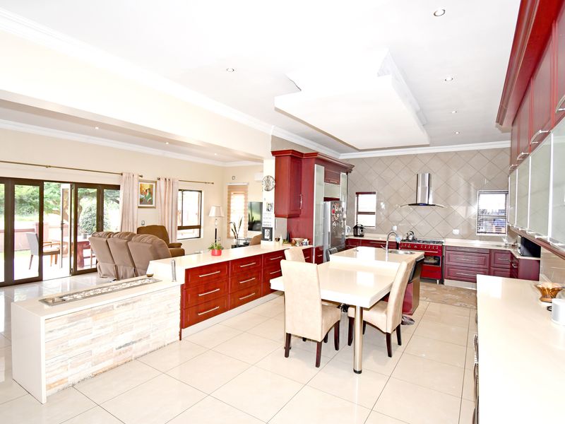 Spacious open-plan kitchen and living area featuring cherry wood cabinetry, a central island, stone tile flooring, and direct access to the outdoor patio.