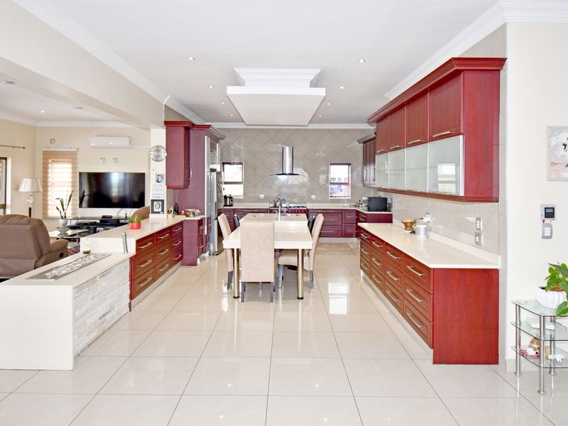 Spacious open-plan kitchen and living area featuring modern cabinetry, stone countertops, a central island, and tiled flooring throughout.