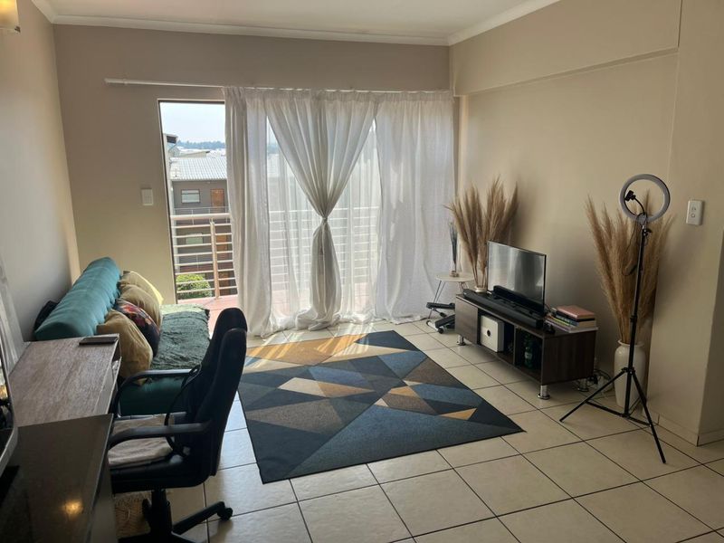 A living room featuring tiled flooring and a sliding glass door providing access to an outdoor balcony area.