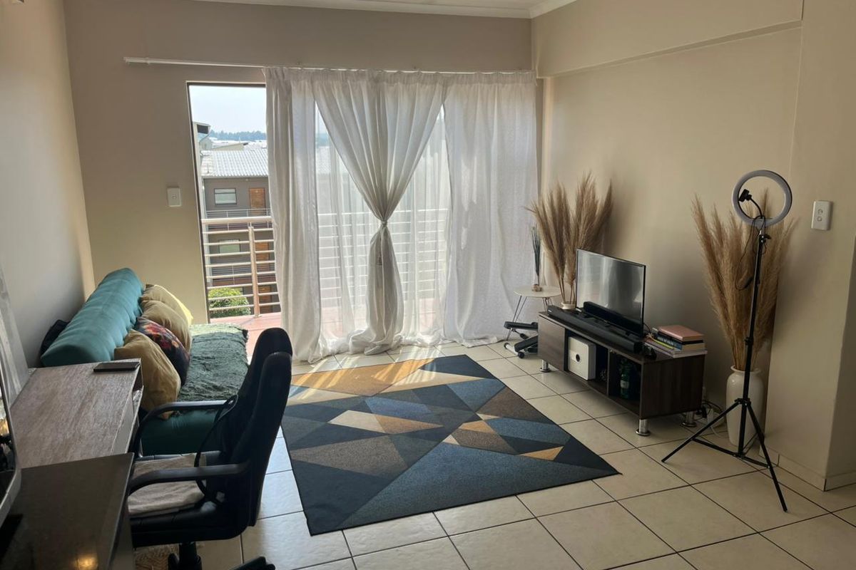 A living room featuring tiled flooring and a sliding glass door providing access to an outdoor balcony area.