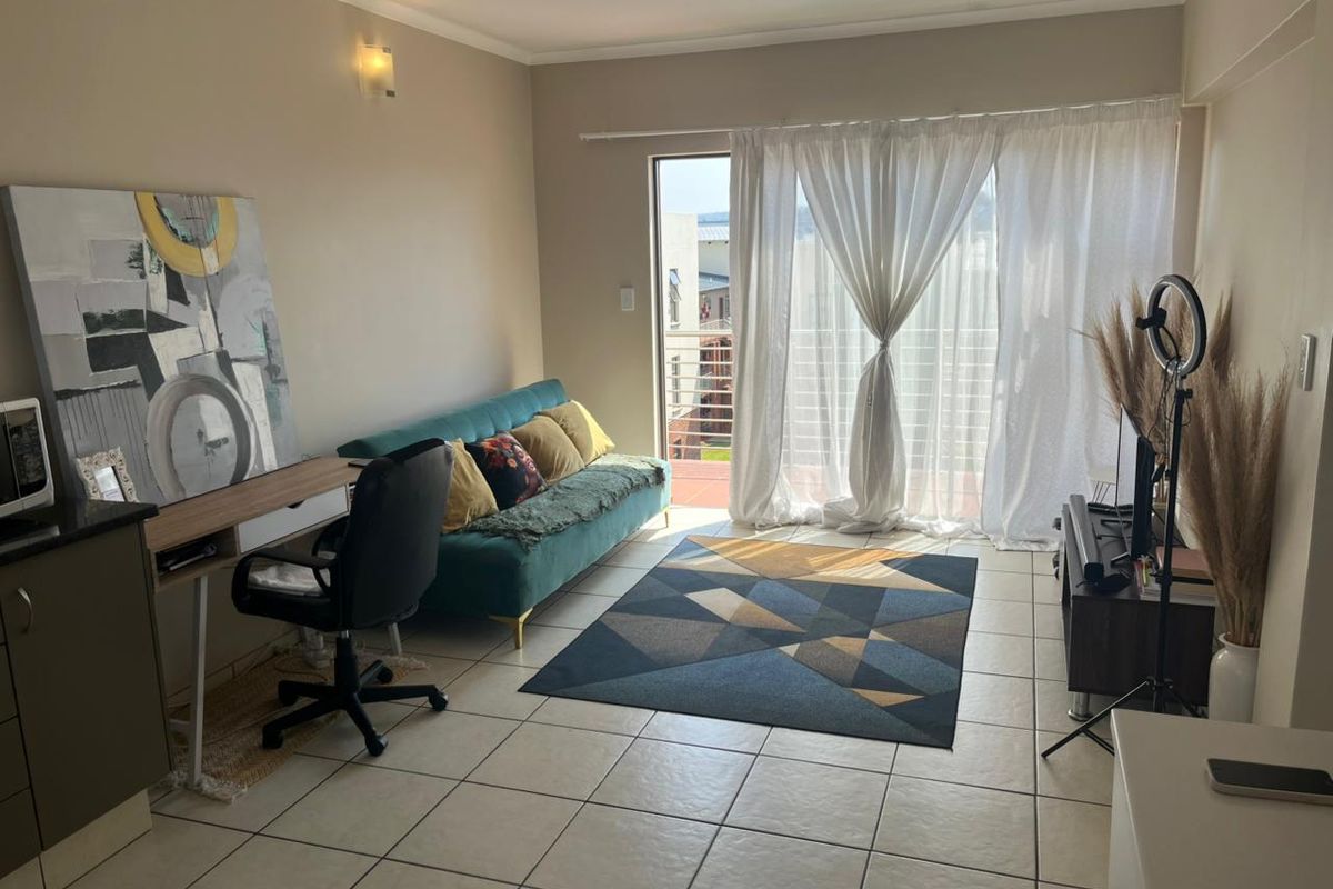 A bright living room featuring tiled flooring and a sliding glass door that provides access to an outdoor balcony area.