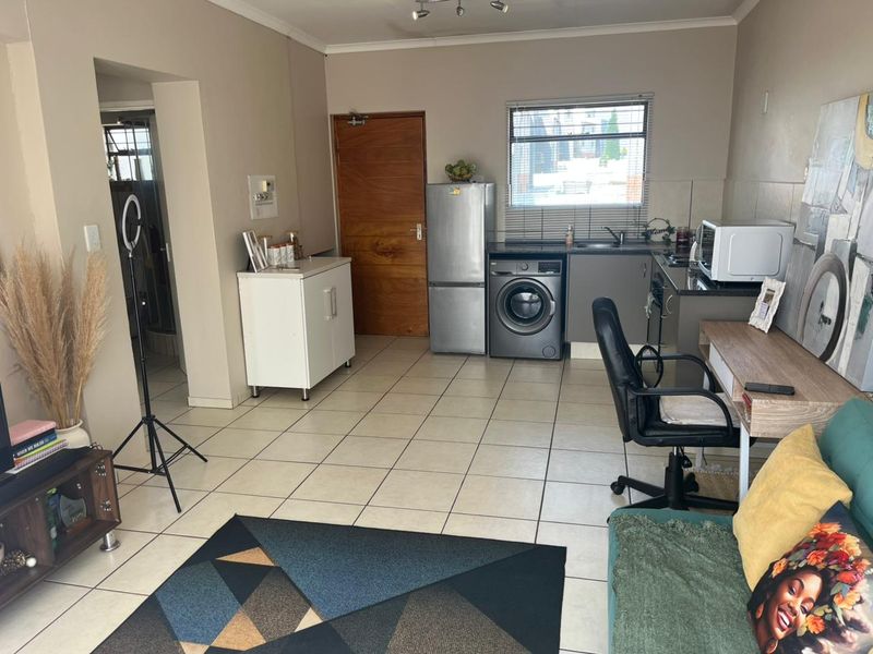 Open-plan living area featuring tiled flooring, a compact kitchen with granite countertops, and integrated laundry space, offering a functional and versatile layout.