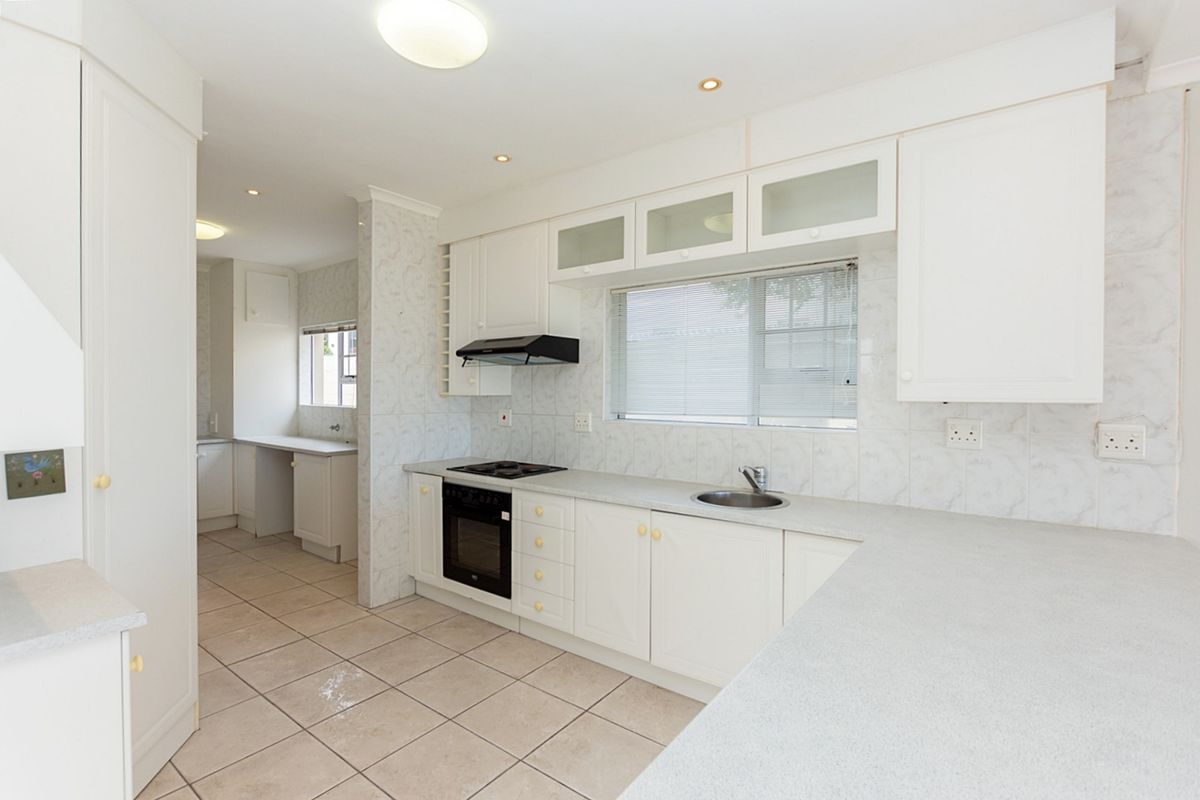 A functional, well-lit kitchen featuring white cabinetry, integrated appliances, tiled backsplash, and a spacious countertop layout, offering a clean canvas for modern updates.