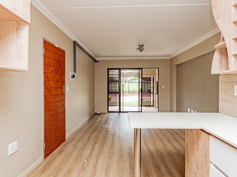 An open-plan living area featuring modern laminate flooring, built-in cabinetry, and a sliding glass door leading to an outdoor space.
