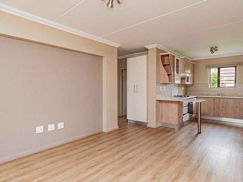 Spacious open-plan living area featuring modern laminate flooring and a well-appointed kitchen with built-in cabinetry, gas hob, and integrated oven.