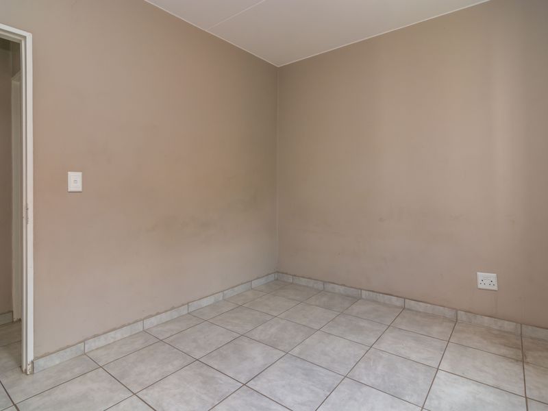 An empty bedroom featuring neutral wall paint and tiled flooring, ready for personalization or staging.