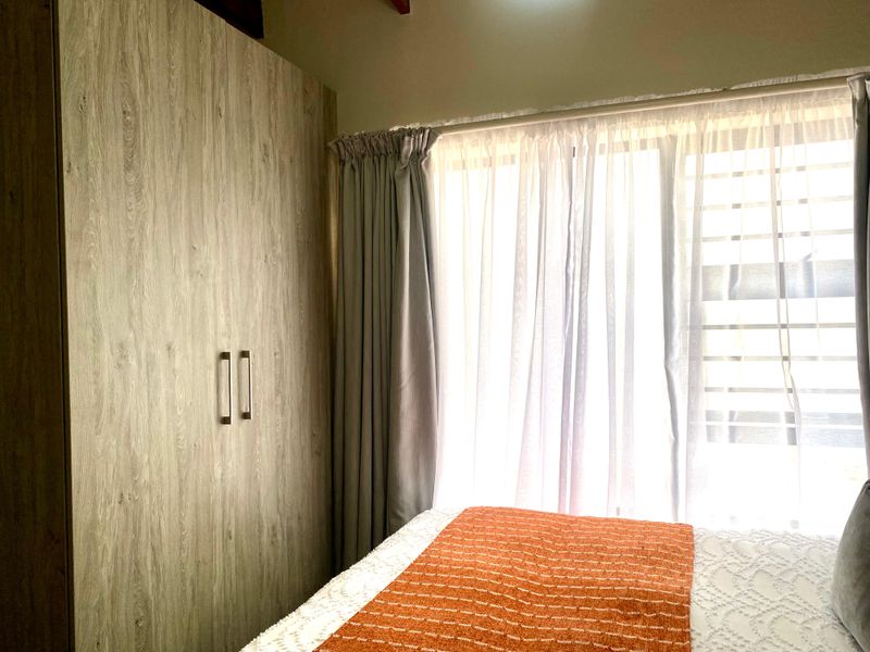 A bedroom featuring a large built-in wardrobe with wood-grain finish and exposed timber rafters, providing a warm and functional living space.
