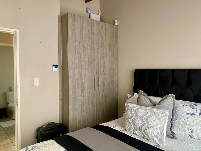 A bedroom featuring a wood-grain built-in wardrobe and an adjacent doorway leading to an en-suite bathroom.