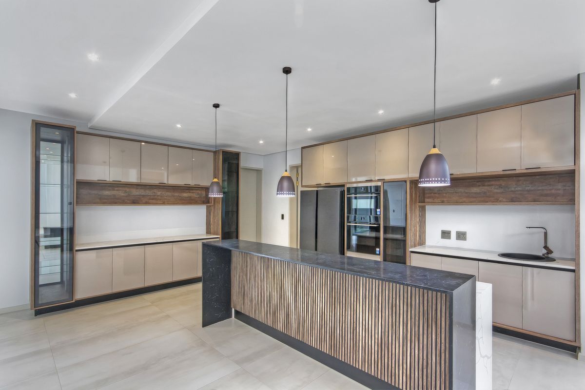 Modern kitchen featuring sleek cabinetry, a central island with stone countertop, integrated appliances, and contemporary pendant lighting in a clean, open-plan layout.