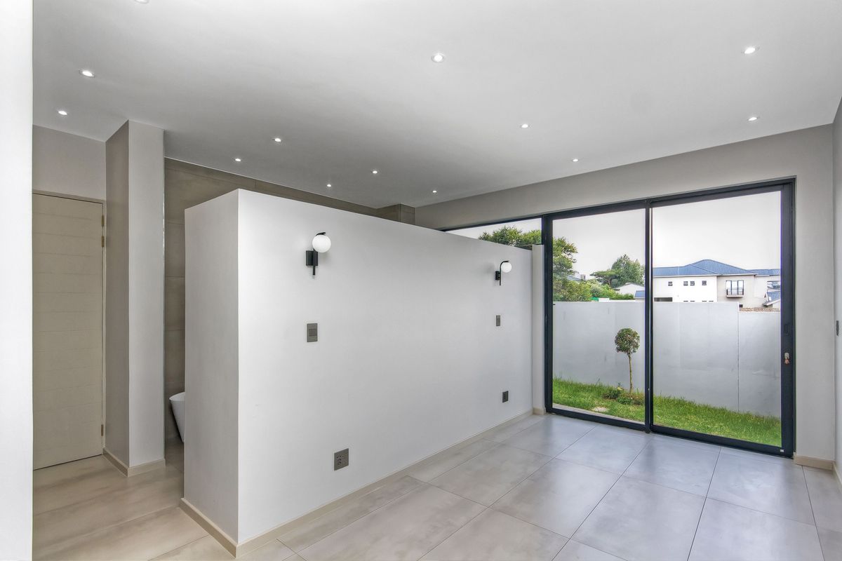 Modern bedroom featuring a central partition wall, recessed lighting, and large sliding glass doors providing direct access to the garden area.