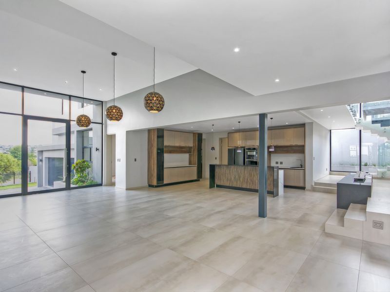 Spacious open-plan living and kitchen area featuring large format floor tiles, modern cabinetry, and floor-to-ceiling windows providing abundant natural light.