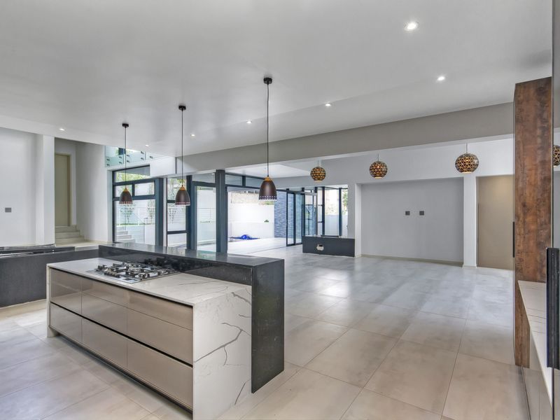 Spacious open-plan living and kitchen area featuring a modern island with gas cooktop, stone countertops, large format tiling, and seamless access to the outdoors.