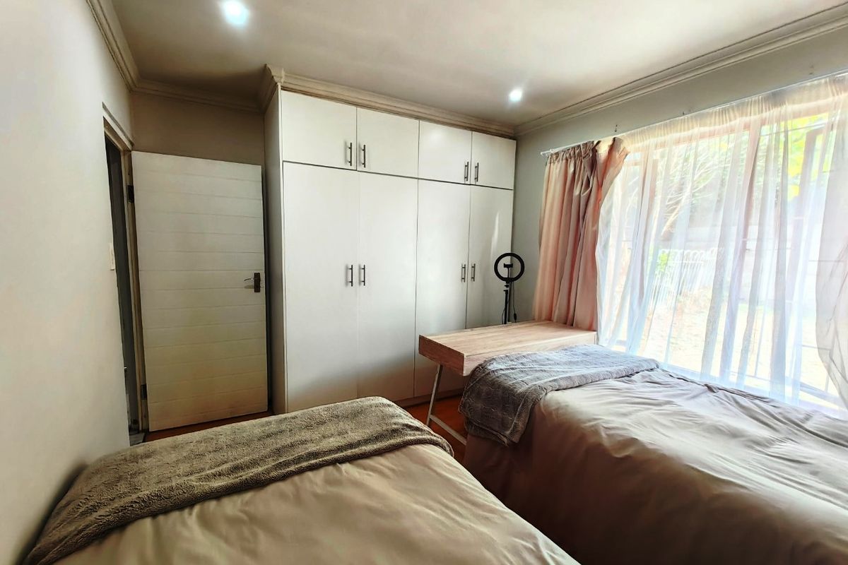 A bedroom featuring built-in cupboards, recessed downlighting, and large windows allowing natural light, providing a functional and comfortable living space.
