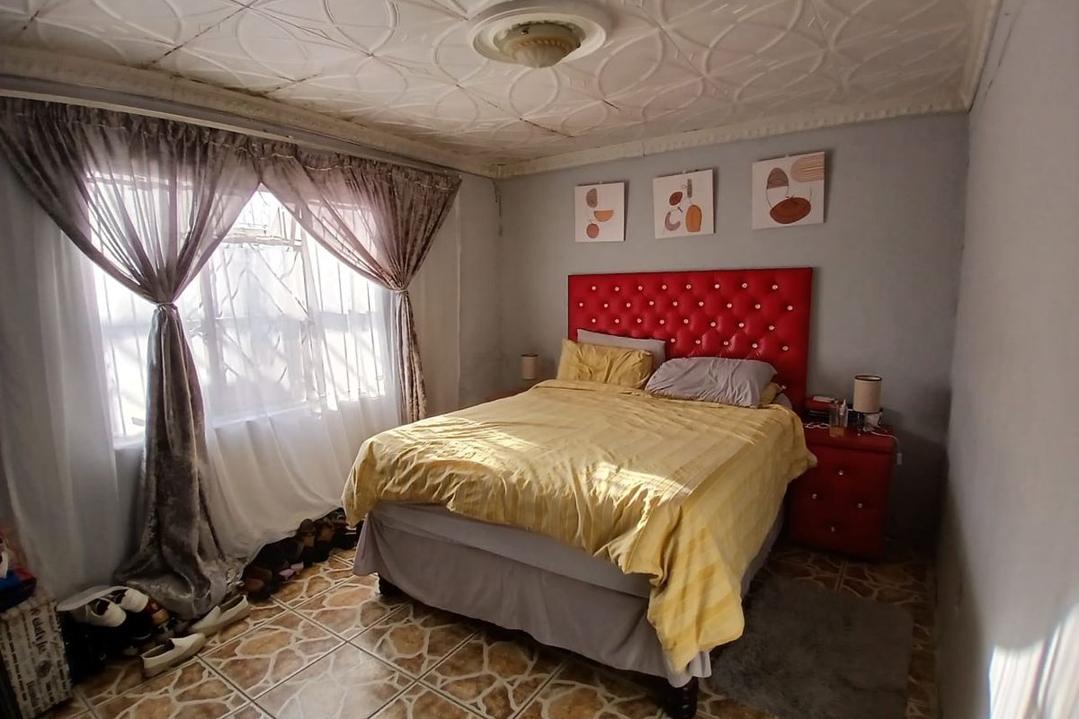 A bedroom featuring decorative ceiling tiles and ceramic floor tiling, requiring cosmetic updates to the walls and ceiling finishes.