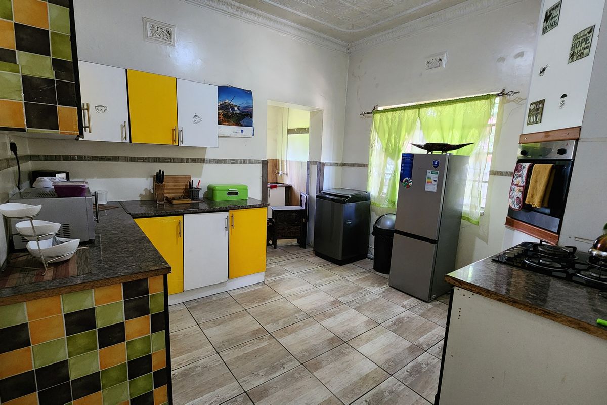 A functional kitchen featuring tiled flooring, laminate countertops, built-in cabinetry, and integrated cooking appliances, requiring cosmetic updates to modernize the space.