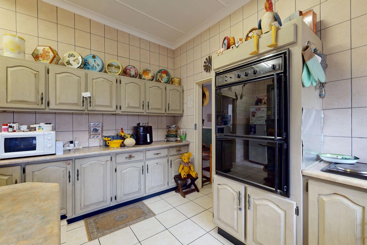 A functional kitchen featuring traditional cabinetry, tiled walls and flooring, and a built-in double oven, offering a classic layout with ample storage space.
