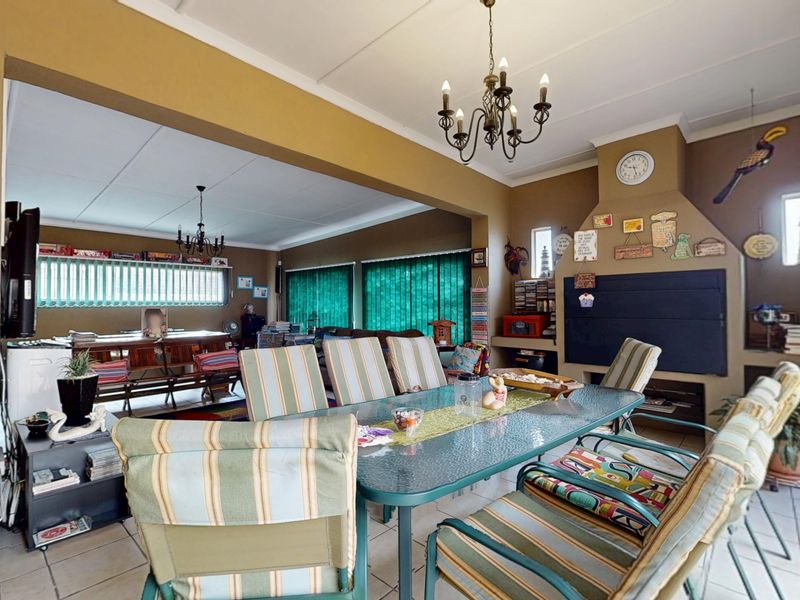Spacious open-plan living and dining area featuring a built-in fireplace, tiled flooring, and classic chandelier lighting.