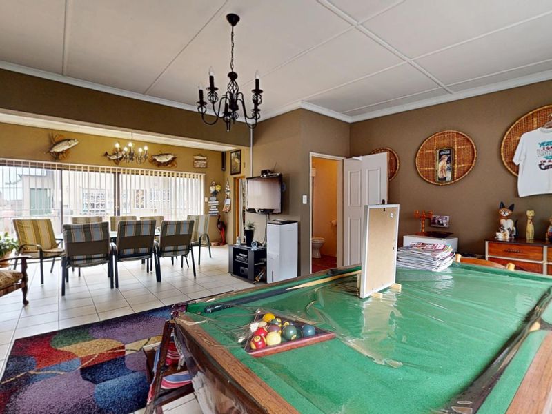 Spacious open-plan living and dining area featuring tiled floors, a chandelier, and large sliding glass doors leading to an outdoor space.