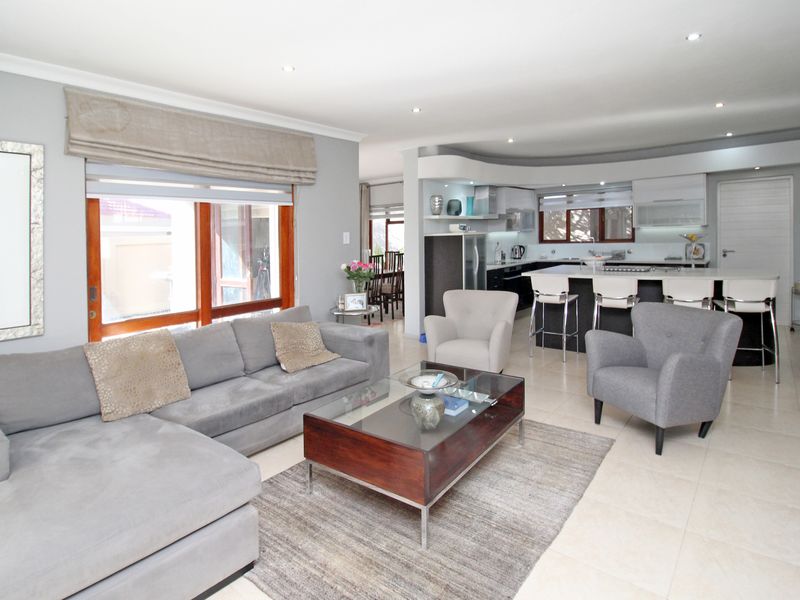 Spacious open-plan living area featuring a modern kitchen with a central island, tiled floors, and seamless flow to the outdoor patio area.