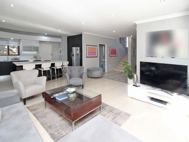 Spacious open-plan living area featuring a modern kitchen with island, tiled flooring, and a staircase leading to the upper level.