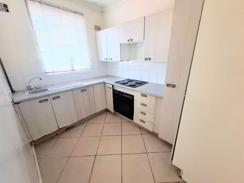 A compact, functional kitchen featuring built-in cabinetry, a tiled backsplash, and integrated oven and hob, offering a blank canvas for modern updates.
