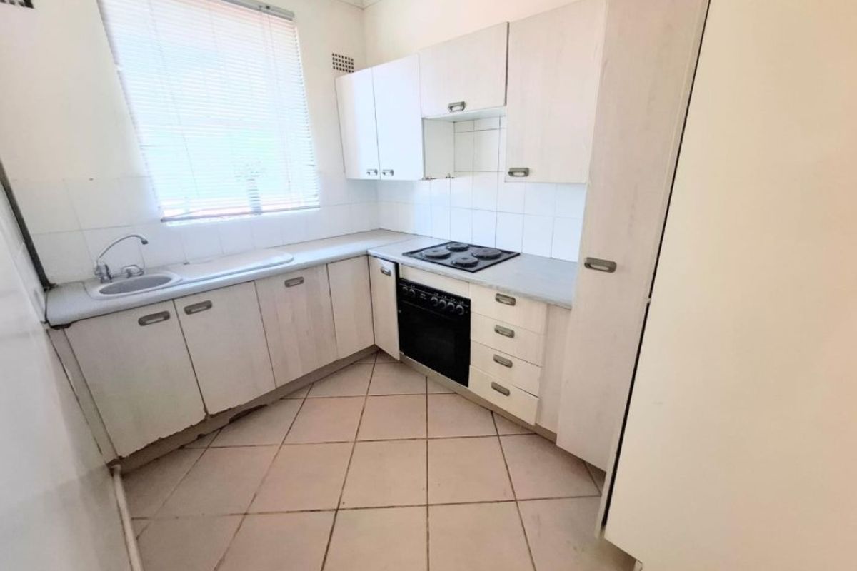 A compact, functional kitchen featuring built-in cabinetry, a tiled backsplash, and integrated oven and hob, offering a blank canvas for modern updates.