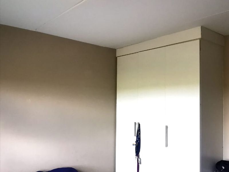 A bedroom featuring a built-in wardrobe and a ceiling light fixture, providing functional storage and lighting within the space.