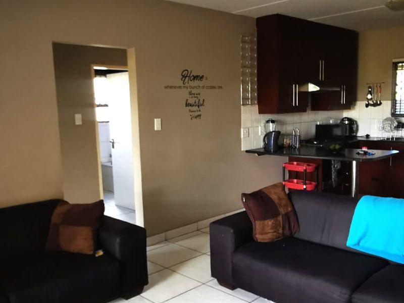 Open plan living area featuring tiled flooring and a functional kitchen with built-in cabinetry and a breakfast counter.