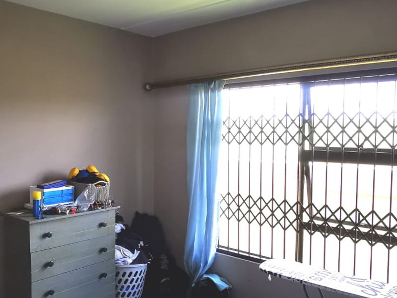 A bedroom featuring a window with a fitted security gate, a ceiling light fixture, and a curtain rod.