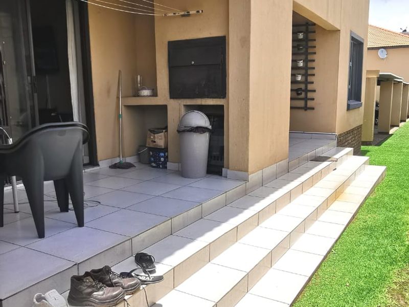 Covered ground floor patio featuring a built-in braai, tiled flooring, and direct access to the garden area.