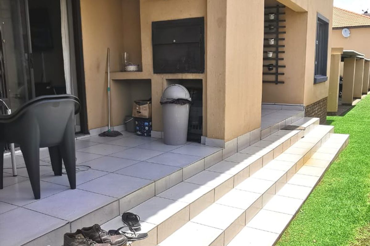 Covered ground floor patio featuring a built-in braai, tiled flooring, and direct access to the garden area.