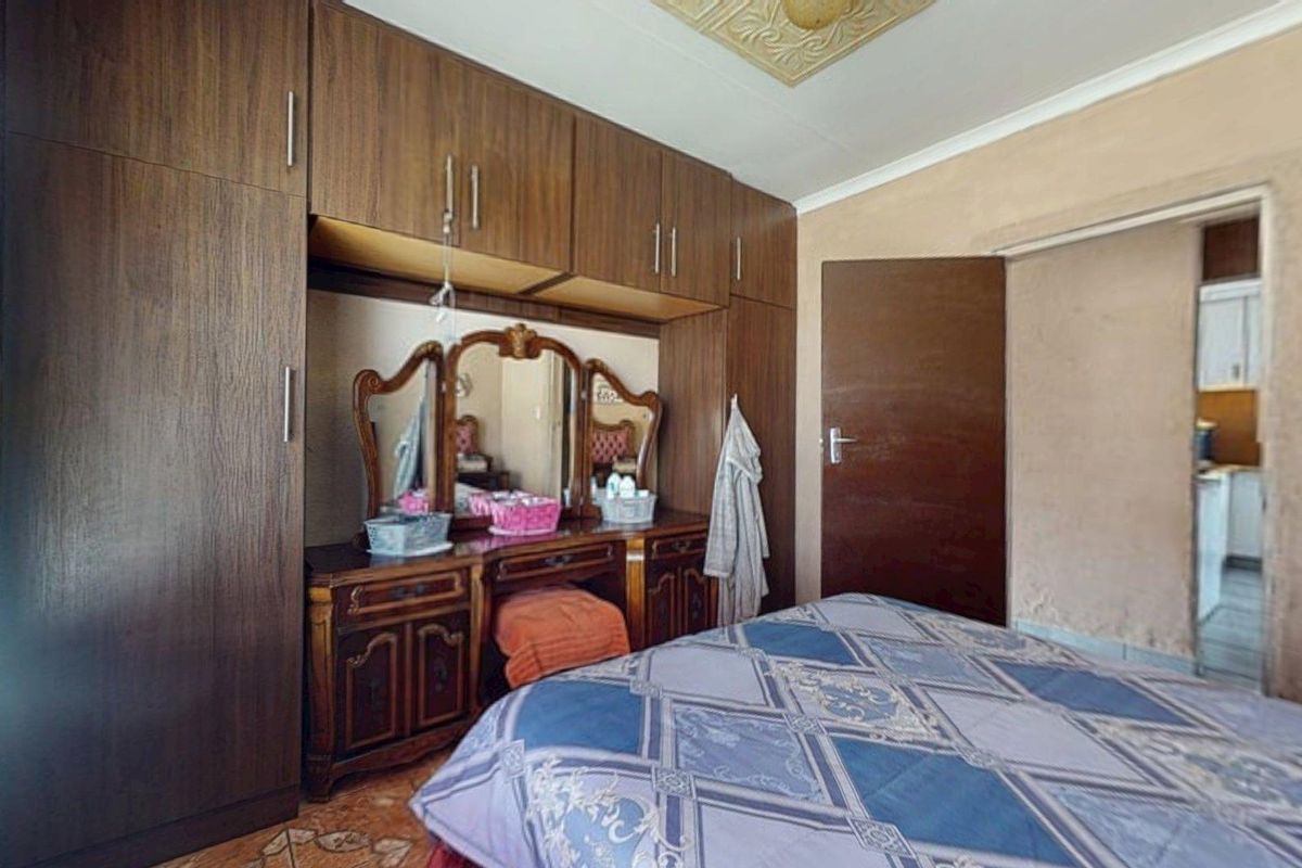 Bedroom featuring extensive built-in wooden cabinetry, decorative ceiling rose, and coving, requiring cosmetic updates to the wall finishes.