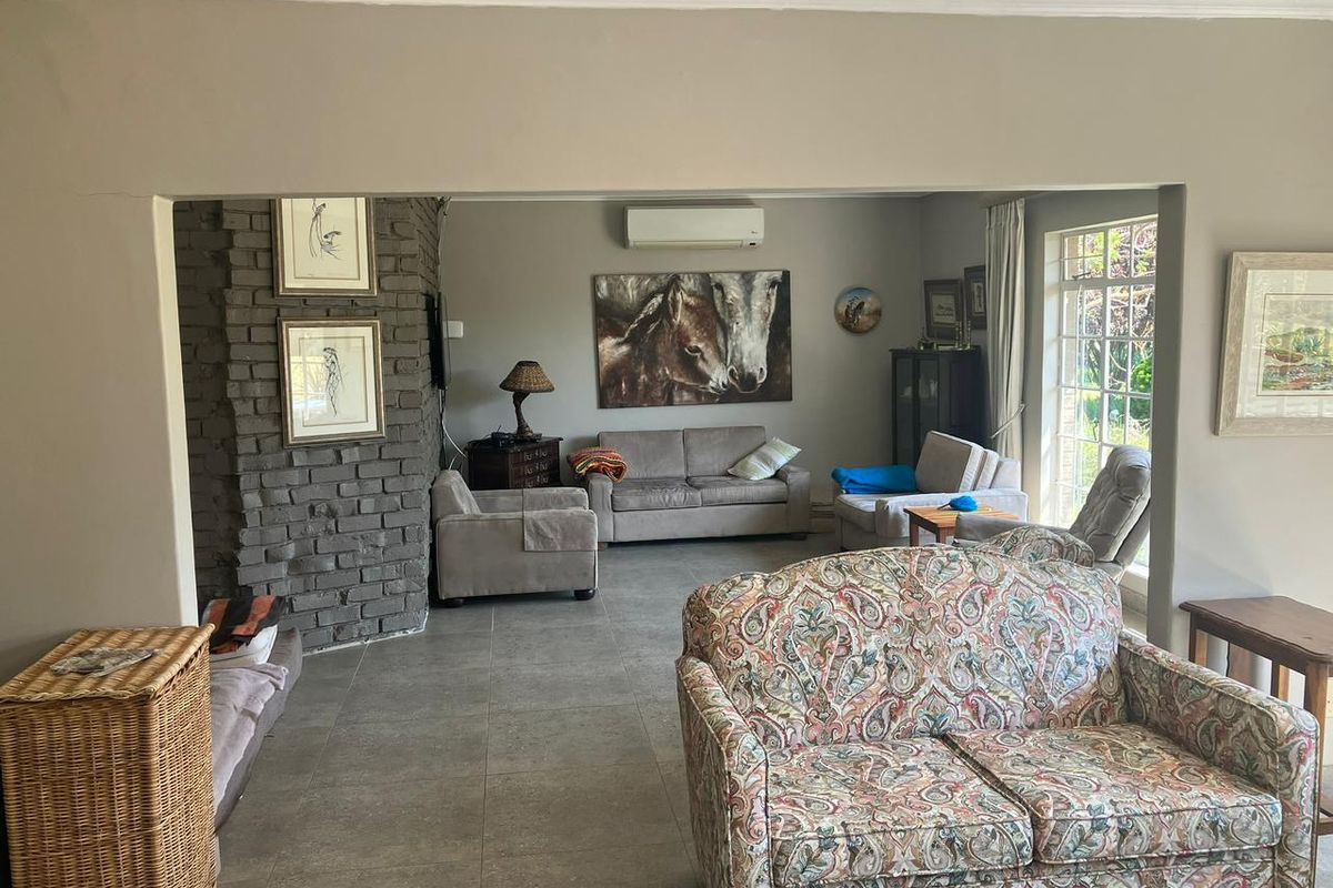 Spacious living room featuring a brick fireplace, tiled flooring, and a wall-mounted air conditioning unit, offering a comfortable and functional living space.