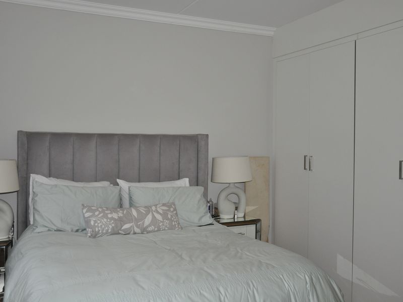 A well-maintained bedroom featuring neutral walls, crown molding, and ample built-in cupboard storage.
