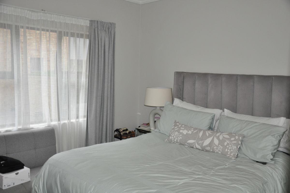 A well-maintained bedroom featuring neutral wall tones and a large window with installed curtain tracks, providing natural light to the space.