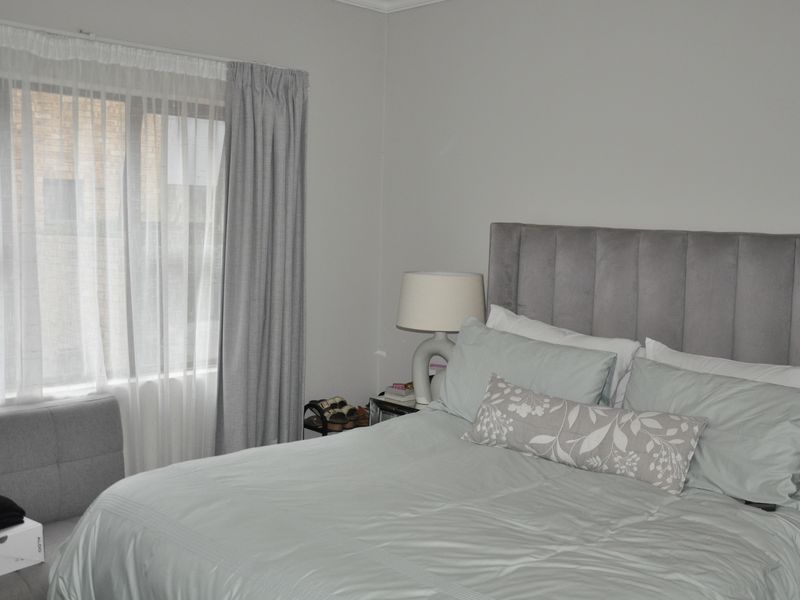 A well-maintained bedroom featuring neutral wall tones and a large window with installed curtain tracks, providing natural light to the space.