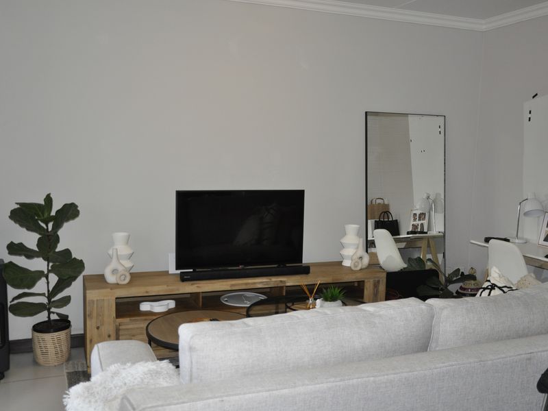 A well-maintained living room featuring neutral walls, tiled flooring, and decorative coving, providing a clean and functional space for relaxation.