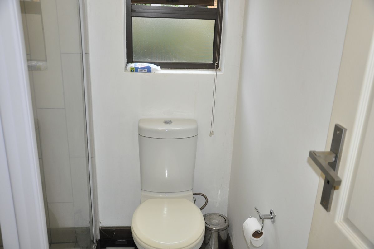 A functional bathroom featuring a standard toilet and a shower enclosure with a small window for natural light and ventilation.
