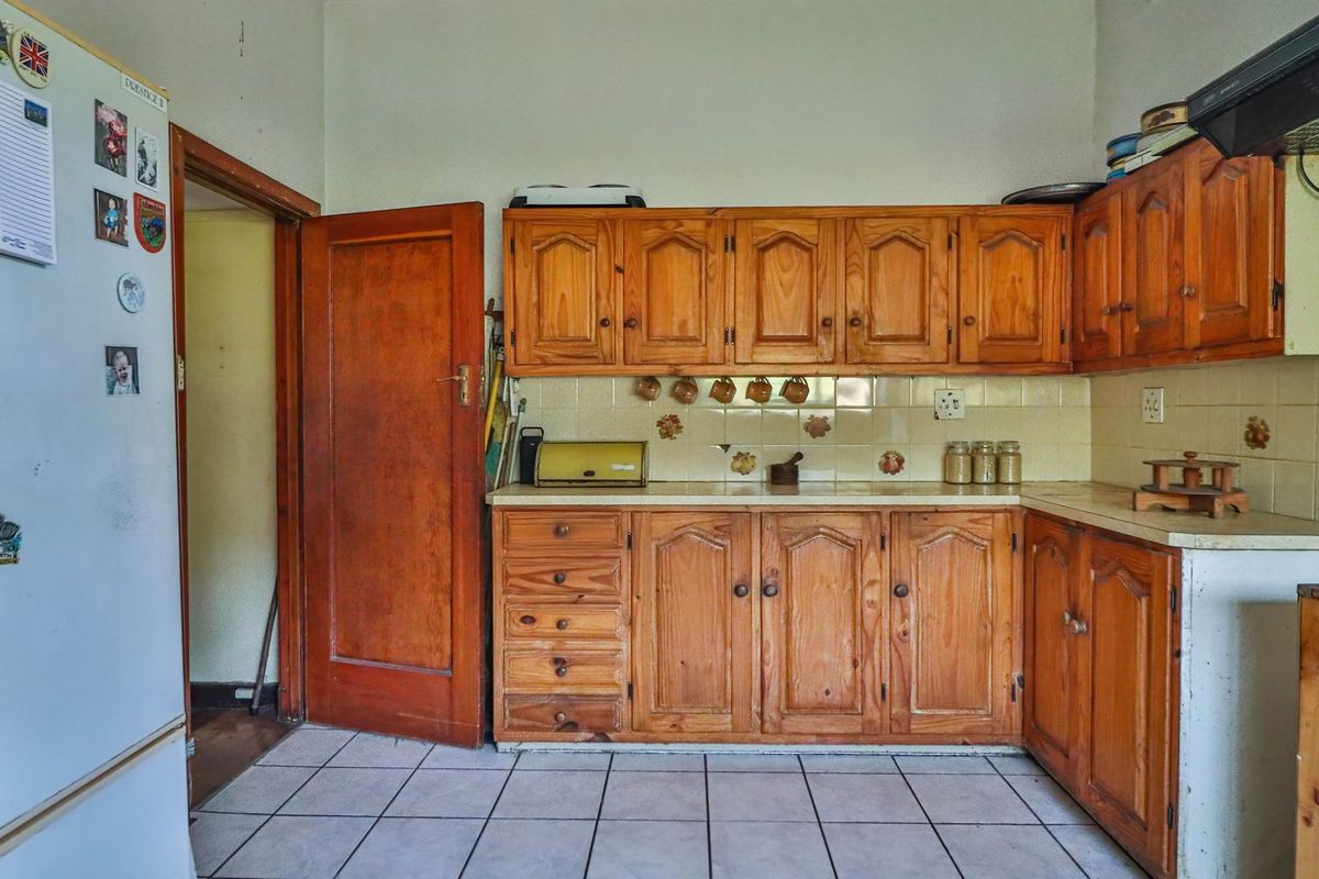 A dated kitchen featuring traditional wooden cabinetry, tiled backsplash, and tiled flooring, offering a functional layout with potential for modernization.