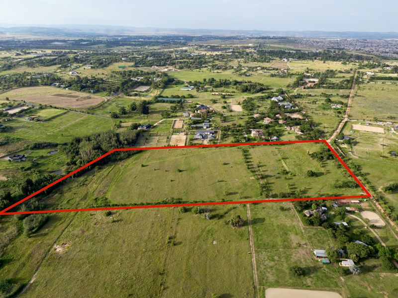 An aerial view of a large, vacant residential plot of land, highlighting the boundaries and surrounding rural landscape.