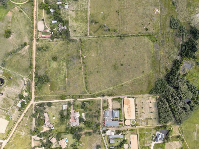 Aerial view of a large residential vacant land plot featuring established fencing, access roads, and surrounding equestrian infrastructure in a rural setting.