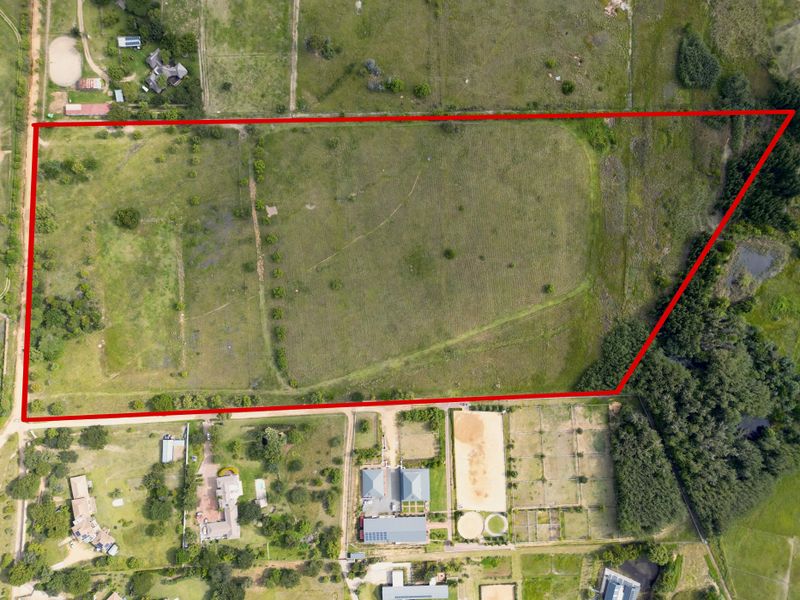 An aerial view of a large, vacant residential plot of land with clear boundary markings, surrounded by established residential properties.