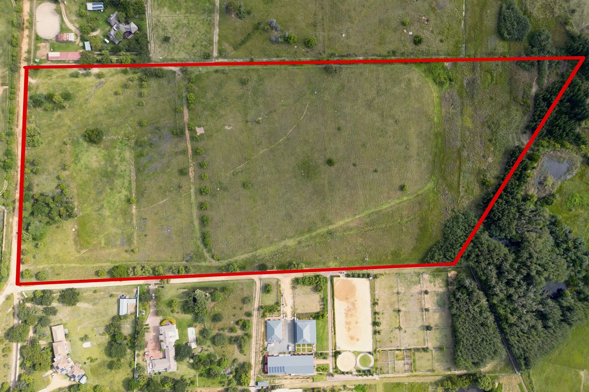 An aerial view of a large, vacant residential plot of land with clear boundary markings, surrounded by established residential properties.