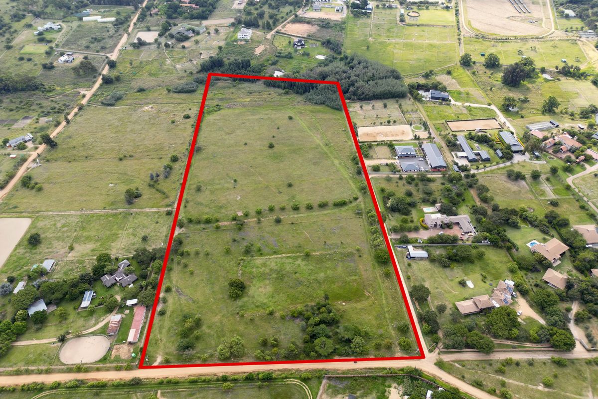 An aerial view of a large, rectangular vacant residential plot outlined in red, situated within a semi-rural estate setting.