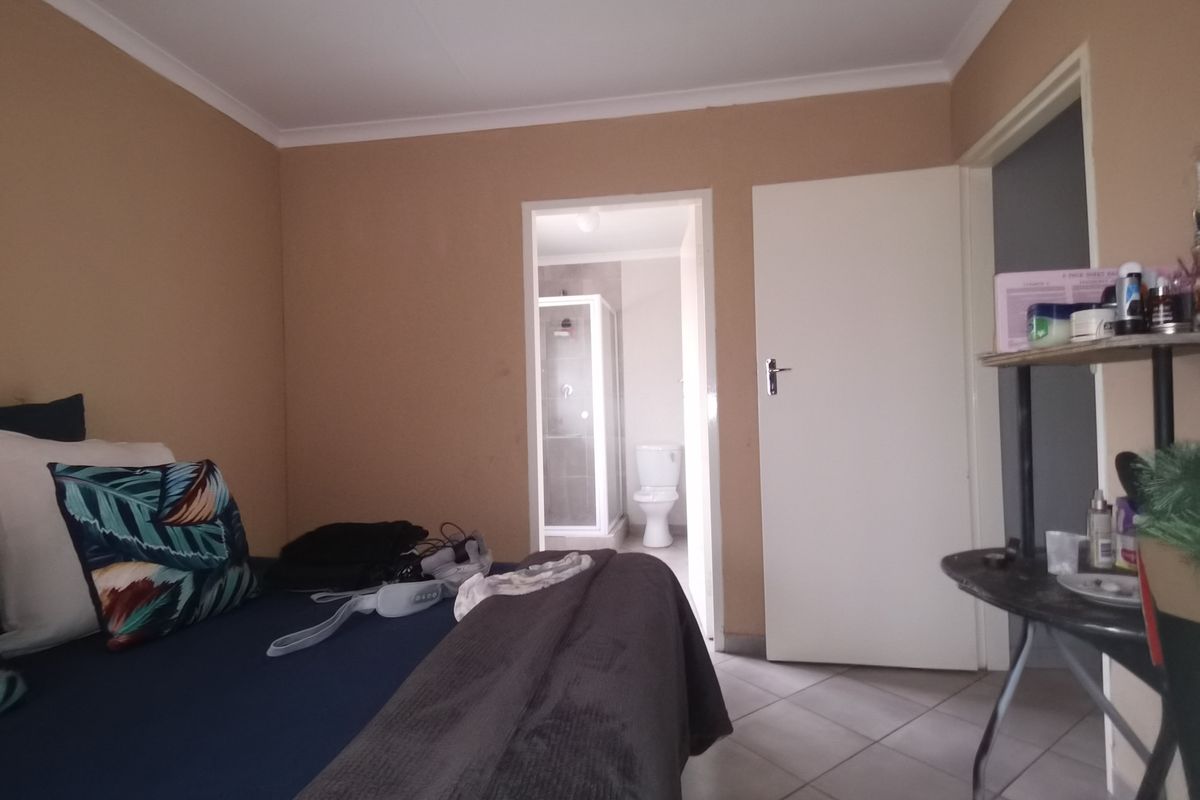 A bedroom featuring tiled flooring and an adjoining en-suite bathroom equipped with a shower and toilet.